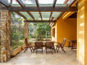 a patio with a table and chairs and a stone wall at Seaside Pineta Retreat in Pula