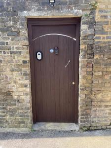 a brown wooden door in a brick wall at Coastal Comfort, Hot Tub Lodge in Margate