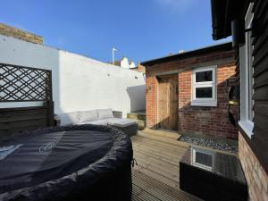 a balcony with a bed and a brick building at Coastal Comfort, Hot Tub Lodge in Margate
