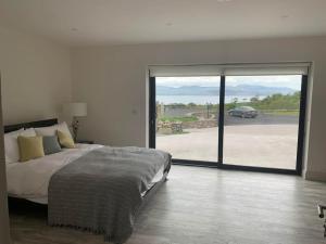 a bedroom with a bed and a large sliding glass door at Kells Bay Apartment in Kells