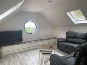 uma sala de estar com um sofá e uma televisão de ecrã plano em Kells Bay Apartment em Kells