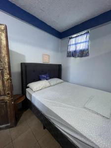 ein Schlafzimmer mit einem Bett in einem Zimmer mit einem Fenster in der Unterkunft Celi’s Ocean Apartment in Caye Caulker