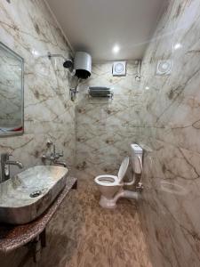 a marble bathroom with a toilet and a sink at HOTEL AARNA in Tezpur