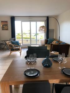 - un salon avec une table en bois et des verres à vin dans l'établissement Appartement vue mer à 100m de la plage au centre de Carantec, à Carantec