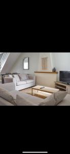 een woonkamer met twee witte banken en een tv bij Southsea Home Stay : 2 Bedroom House with Garden and Hot Tub in Portsmouth
