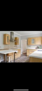 een keuken met houten kasten en een wit aanrecht bij Southsea Home Stay : 2 Bedroom House with Garden and Hot Tub in Portsmouth
