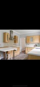 een keuken met houten kasten en een wit aanrecht bij Southsea Home Stay : 2 Bedroom House with Garden and Hot Tub in Portsmouth