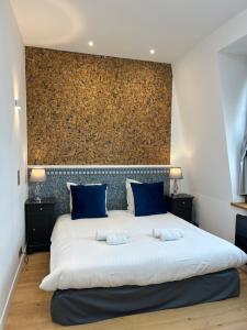 una camera da letto con un grande letto bianco con cuscini blu di Le Royal XIX Dinard vue mer luxe a Dinard