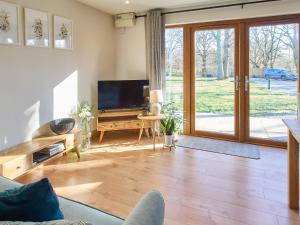 a living room with a tv and a sliding glass door at Host & Stay - Cobnut Barn in Ashford