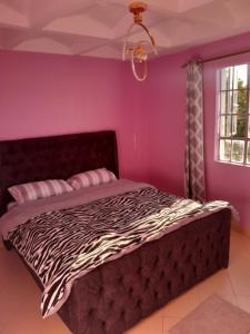 a bedroom with a zebra print bed in a pink wall at Sweet Homes S.Bypass in Kikuyu