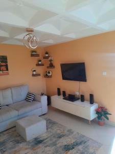 a living room with a couch and a flat screen tv at Sweet Homes S.Bypass in Kikuyu