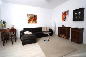 a living room with a black couch and a table at FEWO Odenwald in Breuberg +21 photos