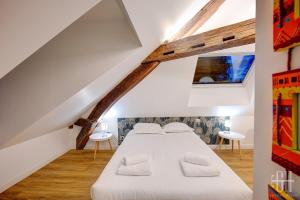 ein Schlafzimmer mit einem weißen Bett auf einem Dachboden in der Unterkunft L'Azur / 100m Gare in Tours