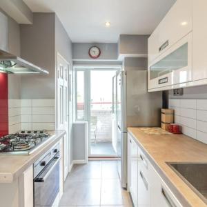 a kitchen with a stove and a clock on the wall at Top Floor 1 Bedroom Apartment with views over London in London
