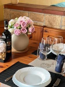 un tavolo con un piatto e un vaso di fiori e bicchieri da vino di Skyscraper Apartment Pontedera a Pontedera