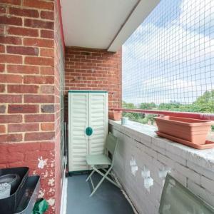a chair sitting on a balcony with a brick wall at Top Floor 1 Bedroom Apartment with views over London in London