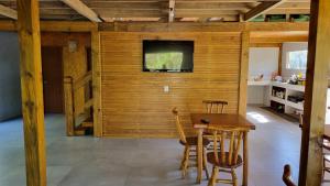 a room with a wooden wall with a table and chairs at Arte da Tribo Hostel & Camping in Praia do Rosa