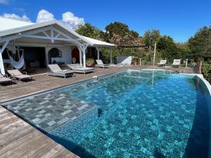 a swimming pool with a deck and a house at Villa Deluxe l'Hacienda Villa vue mer 180 piscine jacuzzi proche plage marina golf pointe des châteaux et casino jardin clos voyage durable in Saint-François