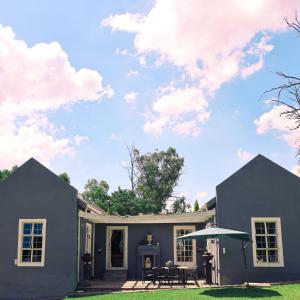 a gray house with a table and an umbrella at Country Retreat in Magaliesburg in Magaliesburg