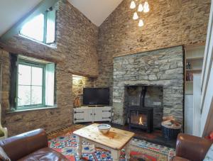 a living room with a stone wall with a fireplace at Fronlefrith Llangrannog in Blaencelyn