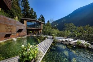 a house with a pool of water in front of it at Hotel Chalet Das Alpenschlössel in Saltusio