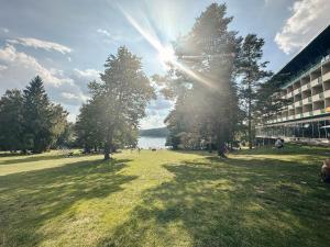 een park met bomen en een gebouw en een meer bij Hotel Medlov in Nové Město na Moravě