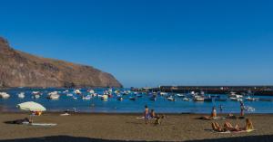a group of people on a beach with boats in the water at Apartamentos Charco del Conde in Valle Gran Rey