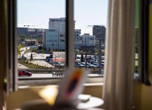 a view of a city from a window with a book at Hotel United PR in Prishtinë