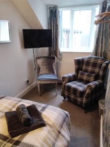 a bedroom with a bed and a chair and a tv at Bagshaw Bed & Breakfast in Bridlington