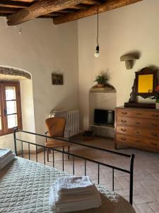 科尔托纳BORGO IN SAN ANGELO的一间卧室配有一张床、一个梳妆台和电视。 更多64张照片