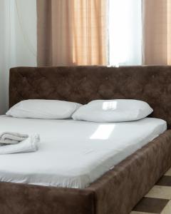 Hotel United PR في بريشتيني: سرير كبير بملاءات ووسائد بيضاء