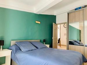 a bedroom with a blue bed and a green wall at La Terrasse des Arènes in Nîmes