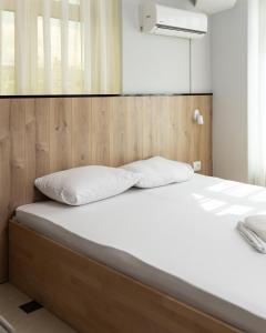 uma cama com cabeceira em madeira e almofadas brancas em Hotel United PR em Pristina