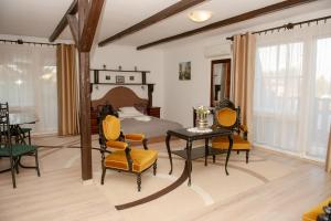 1 dormitorio con 1 cama, mesa y sillas en Hotel Barbizon, en Nyíregyháza