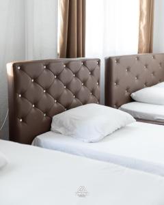 a bed with a brown headboard and a white pillow at Hotel United PR in Prishtinë +17 photos