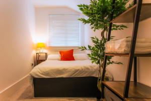 a bedroom with a bed with orange pillows and a plant at Templar Apartment in London