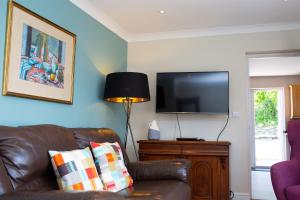 Bryn-y-Mor Apartment Mwnt في Tremain: غرفة معيشة مع أريكة جلدية وتلفزيون بشاشة مسطحة