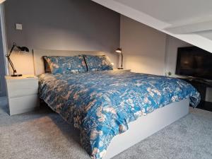 a bedroom with a bed with a blue comforter at The Penthouse NY Loft Apartment in Barmouth