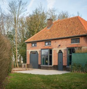 una casa de ladrillo rojo con dos puertas verdes en Huis Octaaf, en Heuvelland