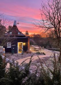 a house in the snow with a sunset in the background at Mousehall Oast in Wadhurst