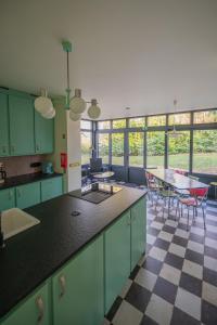una cocina con armarios verdes, mesa y sillas en Huis Octaaf, en Heuvelland