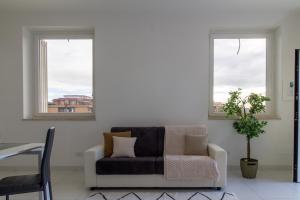a living room with a couch and two windows at Sky Suite Green Pomezia in Pomezia