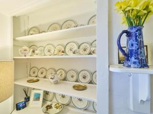 ein Regal mit Platten und einer blauen Vase in der Unterkunft Host & Stay - Claire's Cottage in Kent