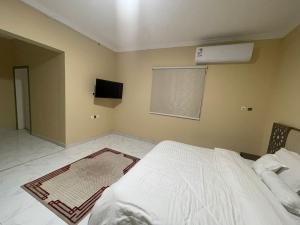 مسكن الجنان للوحدات السكنية في المدينة المنورة: غرفة نوم بسرير ابيض وتلفزيون