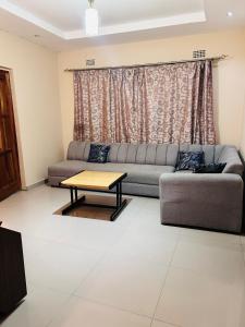 een woonkamer met een bank en een tafel bij Tranquil Room in Apartment in Lusaka