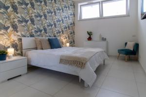 1 dormitorio con 1 cama blanca grande y papel pintado con motivos florales en Sky Suite Blue Pomezia, en Pomezia