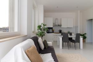 a white living room with a couch and a kitchen at Sky Suite Blue Pomezia in Pomezia