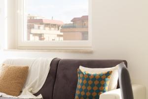 un sofá con almohadas sentado bajo una ventana en Sky Suite Blue Pomezia, en Pomezia
