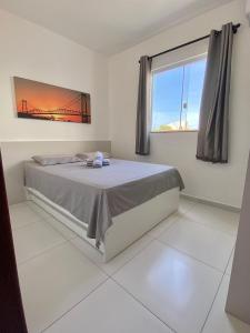 a white bedroom with a bed and a window at Residencial Diva in Florianópolis
