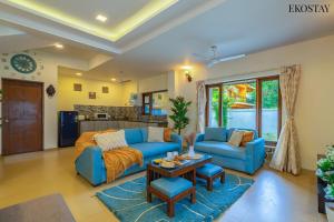 MarmagaoにあるEKO STAY - Solace Villa I Charming Villa close to Candolim Beachのリビングルーム(青いソファ、テーブル付)